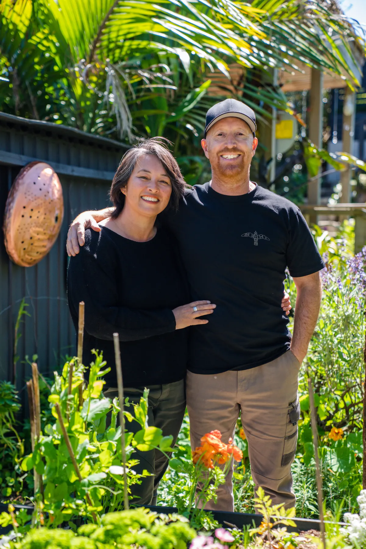 Isaac and Lara Weston in their Matua garden, surrounded by planting and copper sculpture