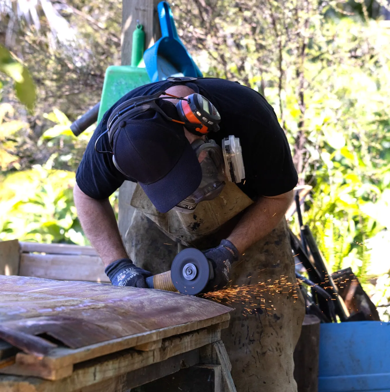 Isaac Weston grinding a copper sheet in his Matua workshop, sparks flying